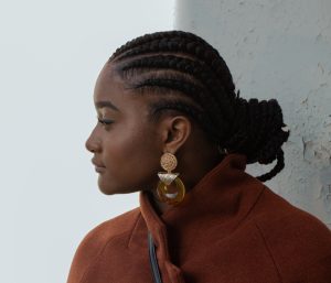 Side portrait of a woman with tight-looking cornrows.