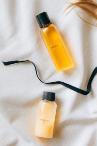 A bottle of shampoo, a black ribbon and a bottle of conditioner.