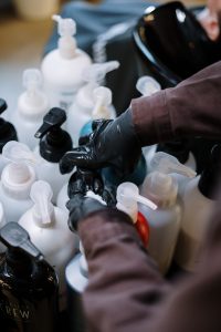 Hair products being handled by someone wearing black nitrile gloves